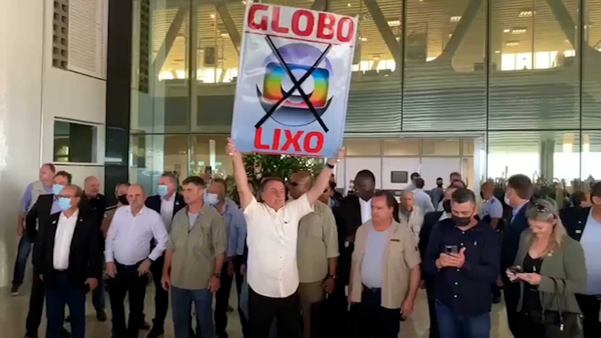 Bolsonaro estendendo cartaz de Globo Lixo em aeroporto